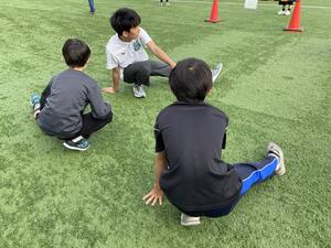 受付を済ませた小学生は、陸上部員と一緒にウォーミングアップ